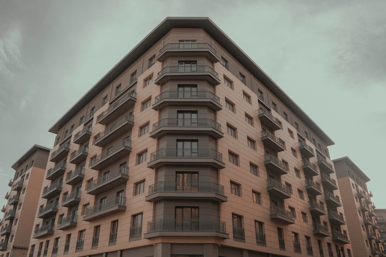 about-01 Corner view of a modern residential building with balconies against a cloudy sky.