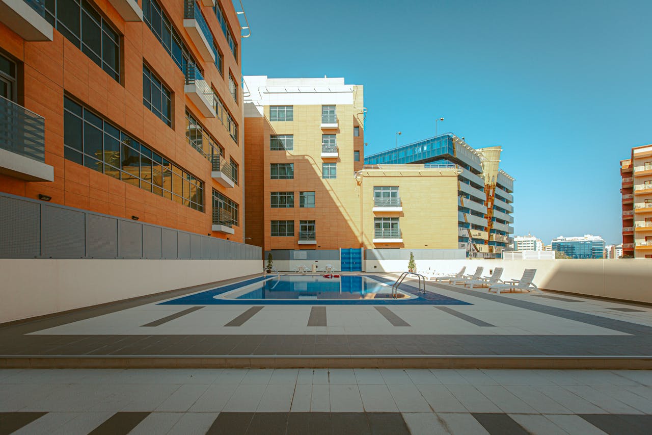 services-01 A cityscape showcasing a rooftop pool surrounded by modern high-rise buildings under a clear blue sky.