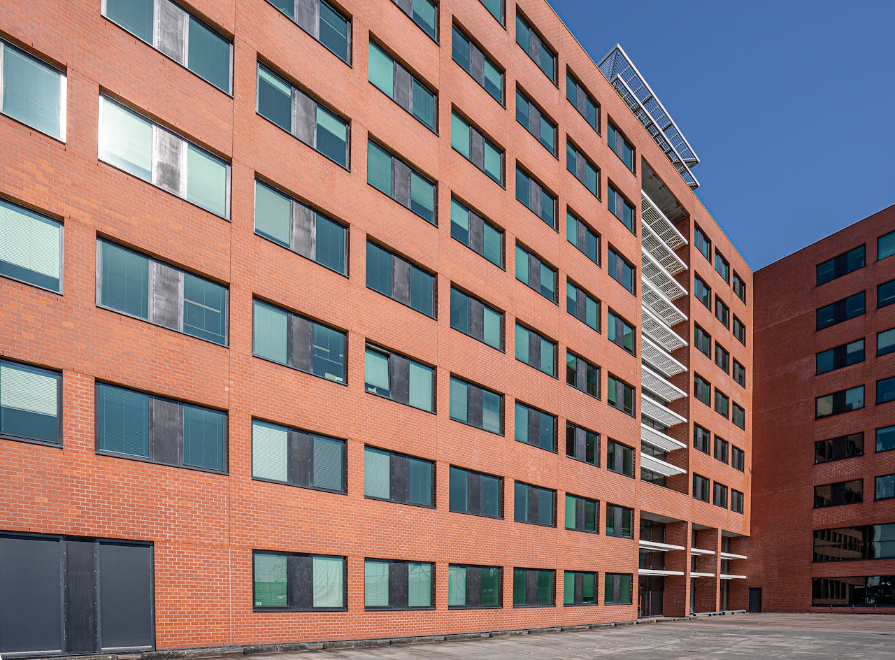 services-02 Exterior view of a modern brick building with glass windows under a clear blue sky.